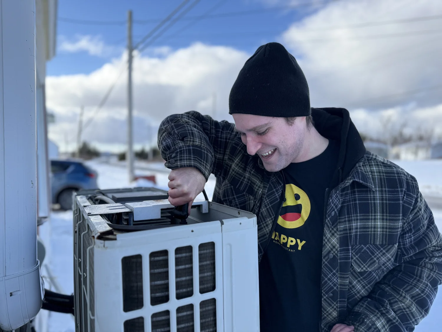 Happy Home Assistant team member working on an outdoor heat pump