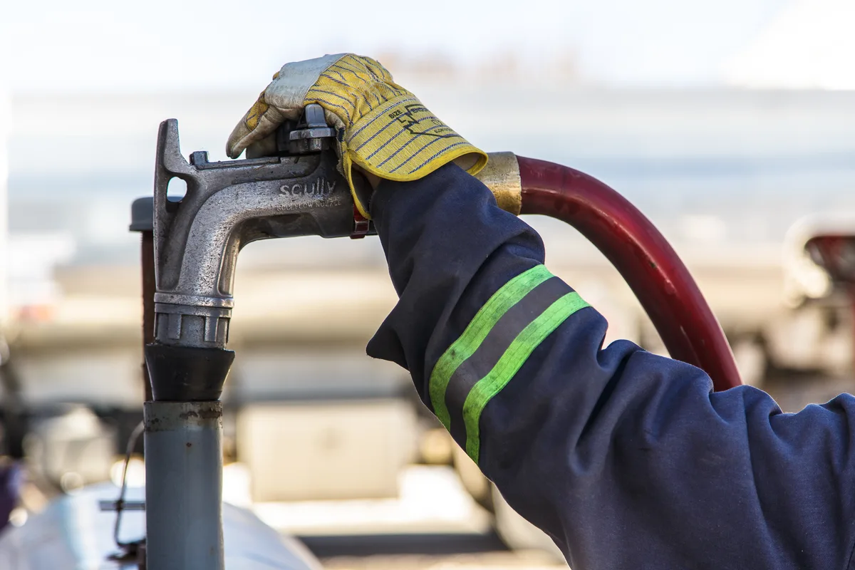 A gloved hand holding a heating oil delivery nozzle.