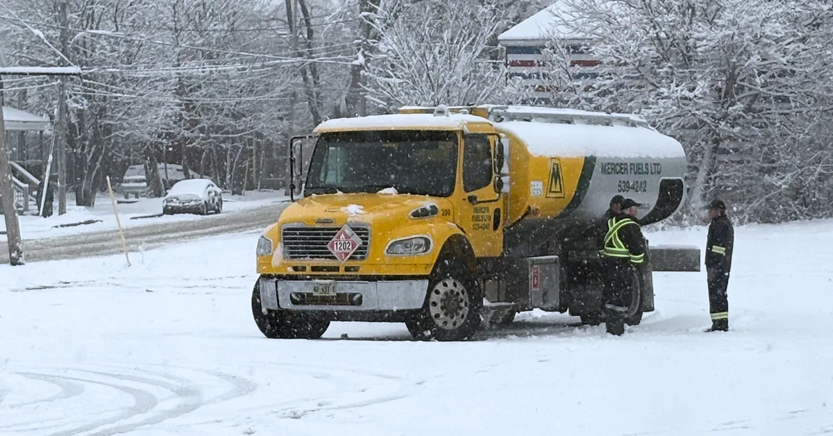 Two people beside a Mercer Fuels truck in the snow.